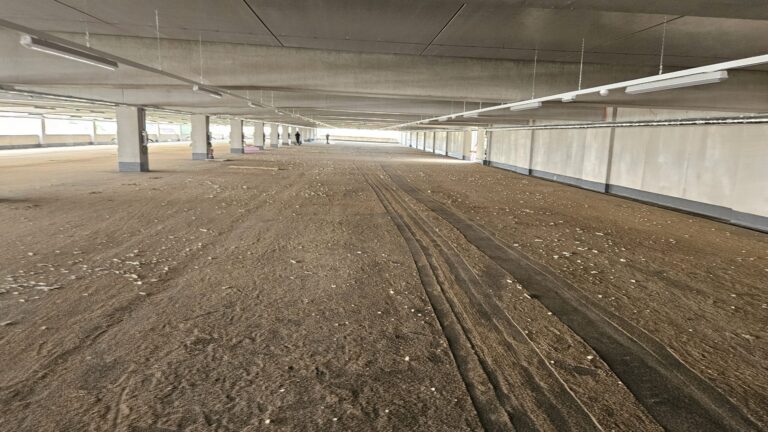 Parkdeck mit Sand, Splitt und Reifenspuren vor der Reinigung