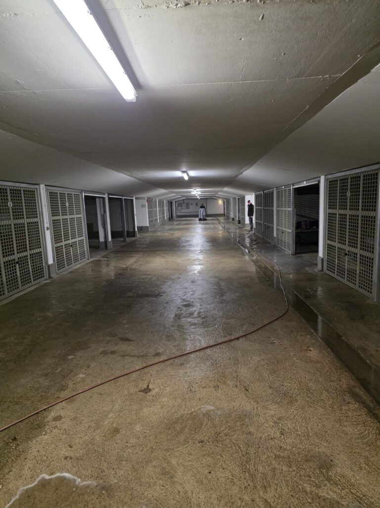 Kellergang einer Tiefgarage mit nassem Boden während der Reinigung