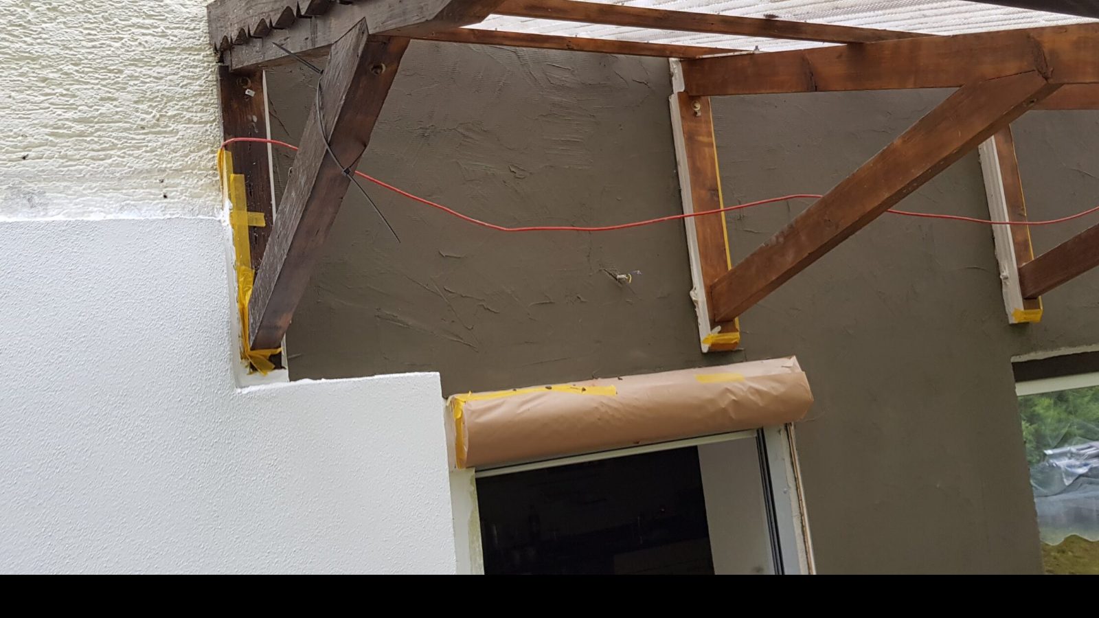 Anschluss der Wand an das Vordach, Balken und Rahmen abgeklebt