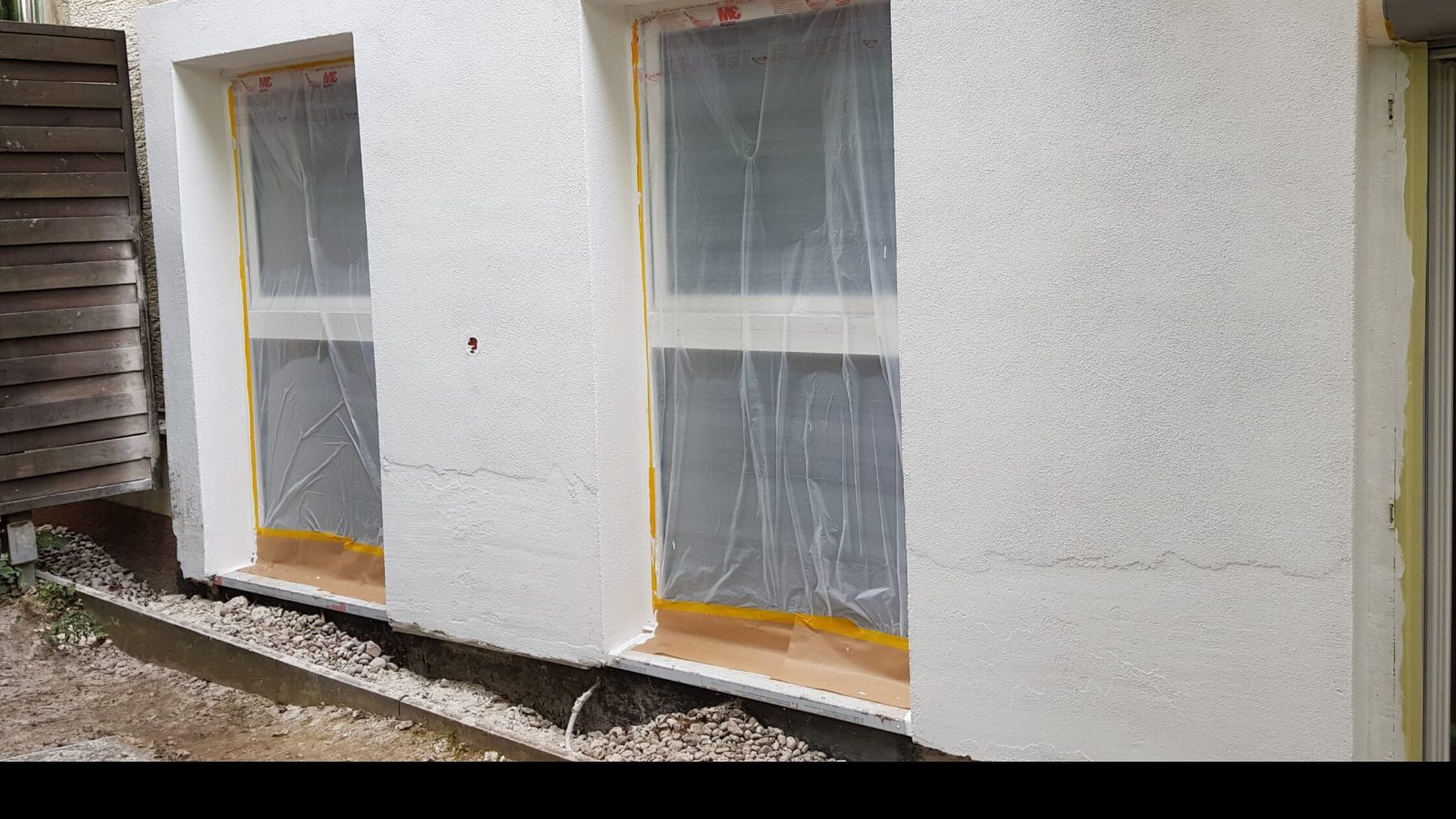 Außenwand eines Wohnhauses während der Arbeiten, Fenster abgeklebt