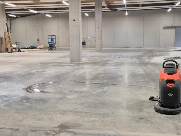 Bauendreinigung: Scheuersaugmaschine im Einsatz auf dem Betonboden einer Gewerbehalle