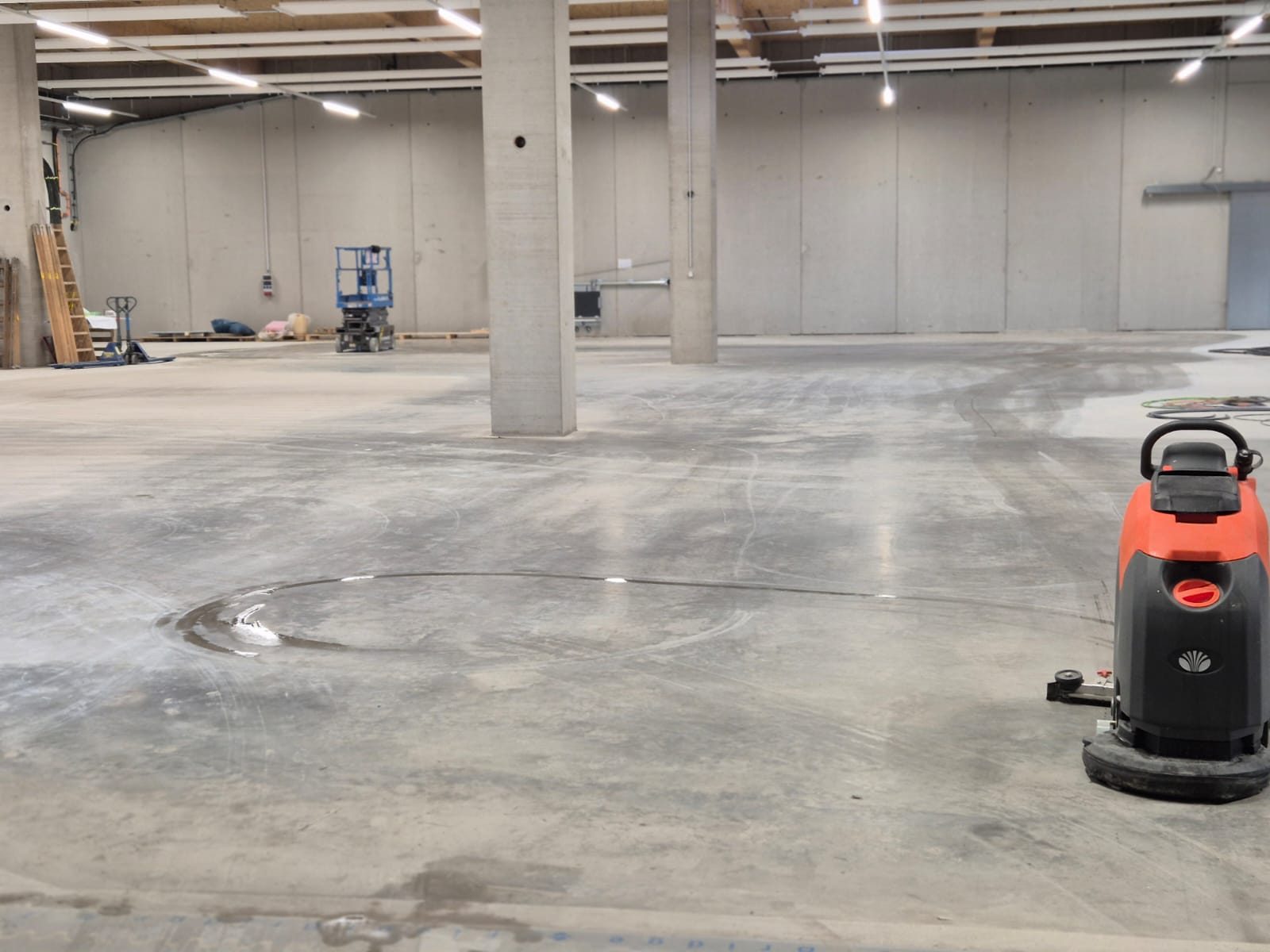 Scheuersaugmaschine in einer großen Halle mit Betonboden