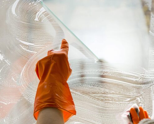 Glas- und Fassadenreinigung Ebersberg: Hand mit Gummihandschuh reinigt eine Fensterscheibe