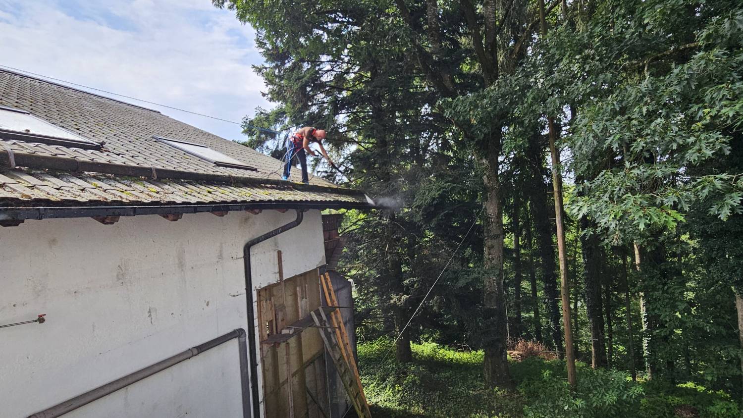 Gebäude am Waldrand während der Dachreinigung
