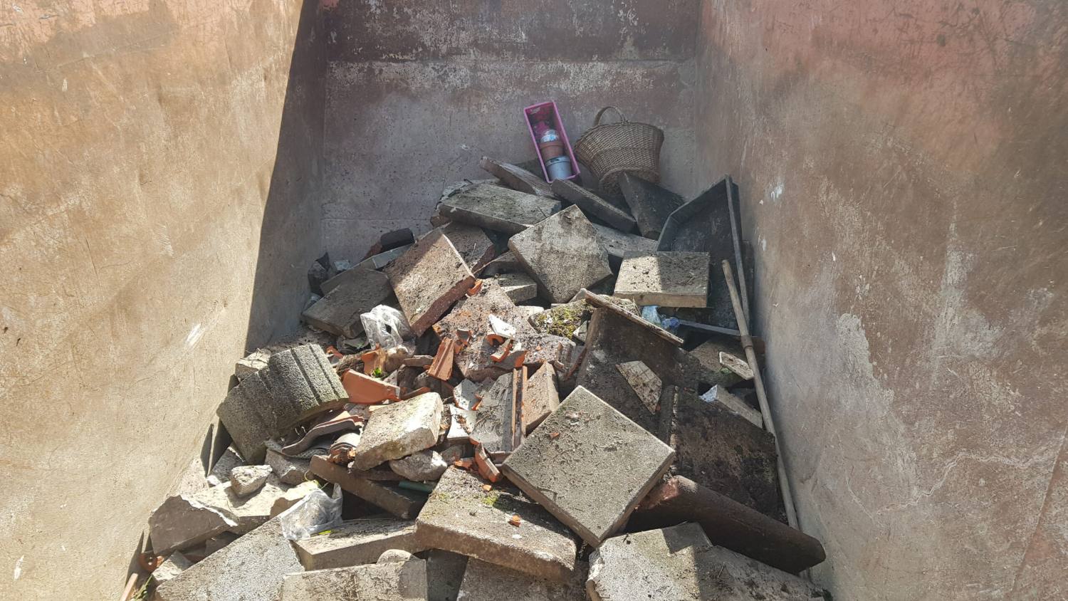 Raumecke voller Bauschutt und Ziegel vor der Räumung