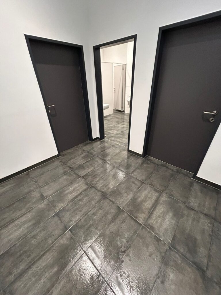 Flur mit dunklen Türen und frisch gereinigten Bodenfliesen
