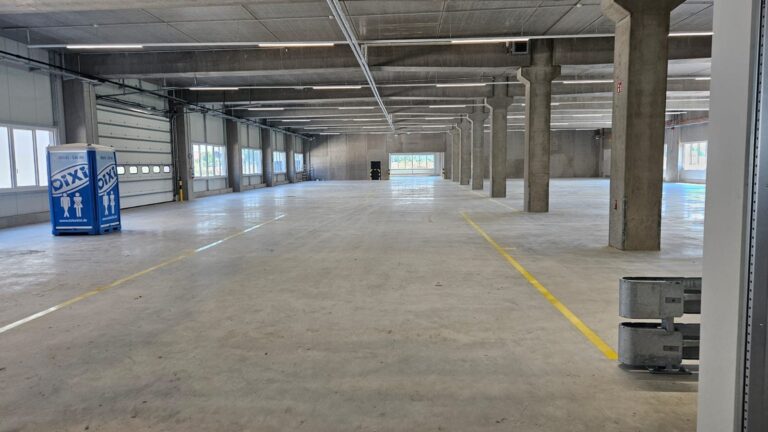 Weite Gewerbehalle mit gereinigtem Betonboden und Fahrbahnmarkierung