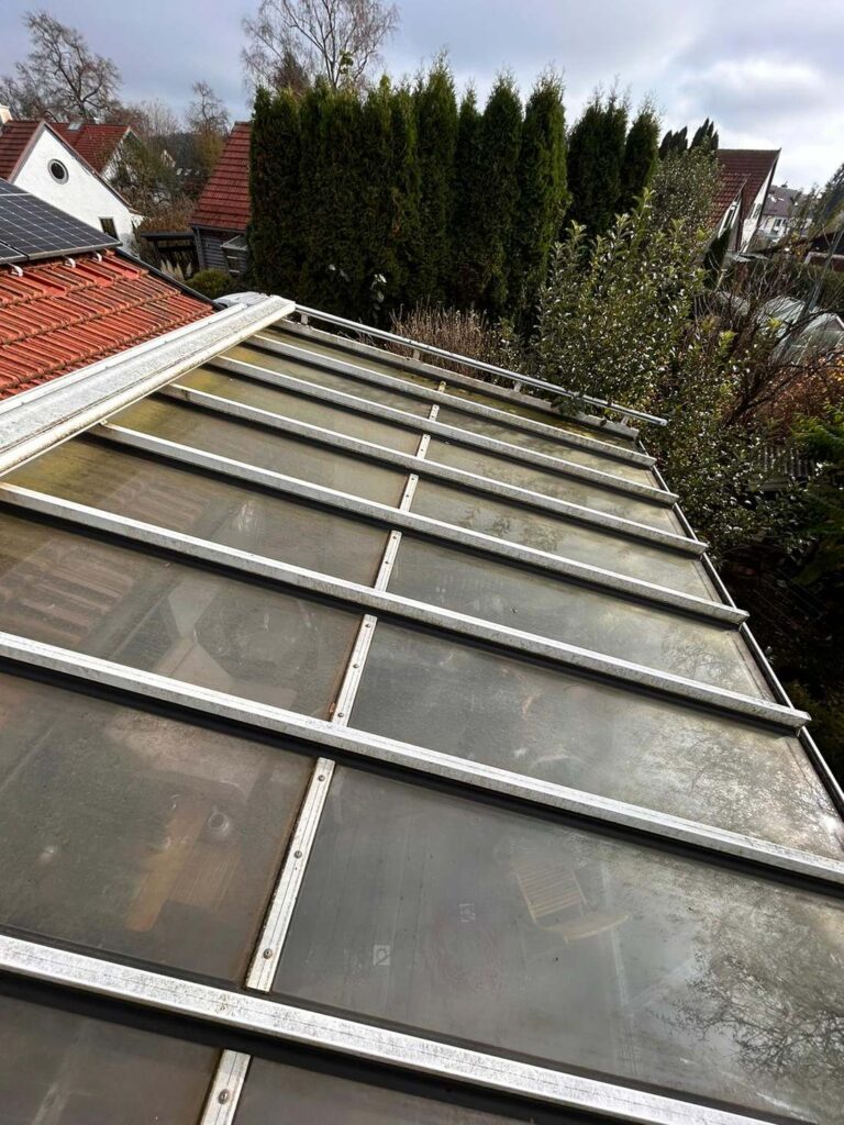 Glasdach mit Grünbelag vor der Reinigung