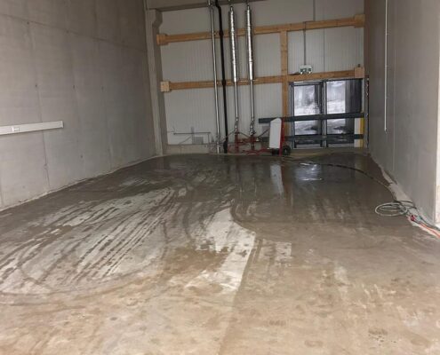 Frisch nass gereinigter Betonboden einer Gewerbehalle