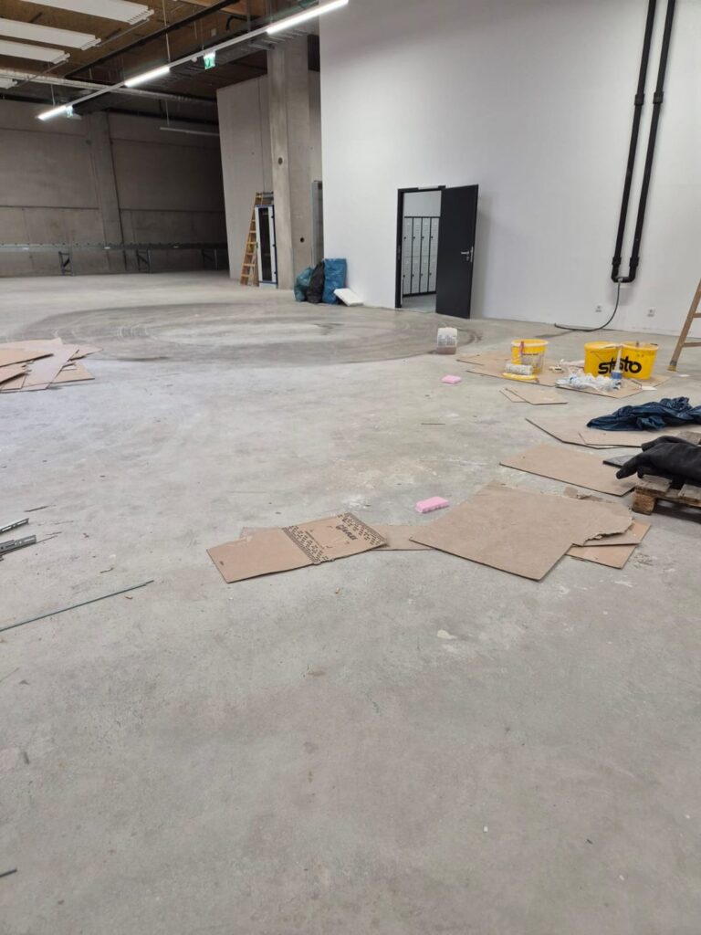 Hallenboden mit Kartonresten und Baumaterial vor der Bauendreinigung