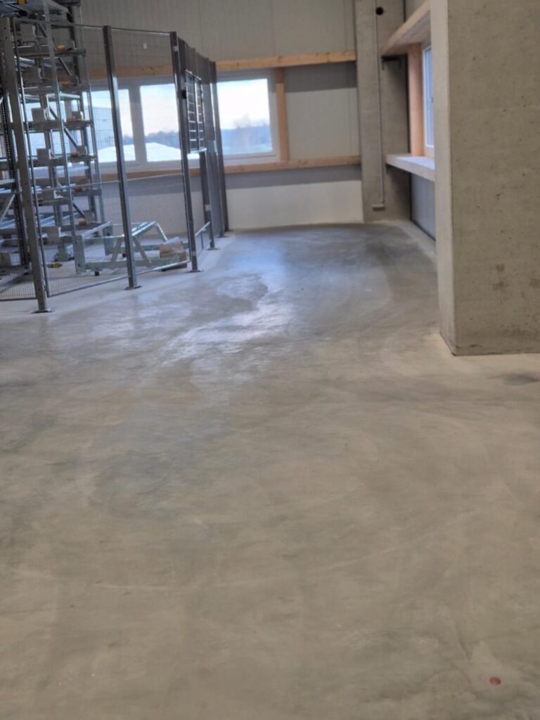 Baustellenreinigung: gereinigter Hallenboden neben einem Lagerregal