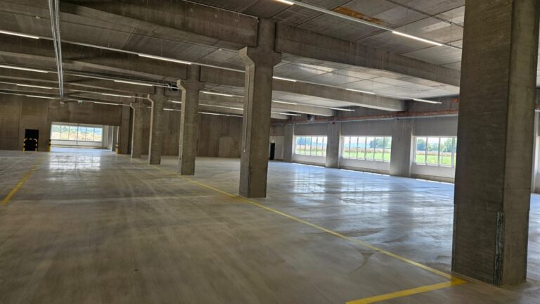 Parkdeck mit Betonstützen und Ladepunkten für Elektroautos