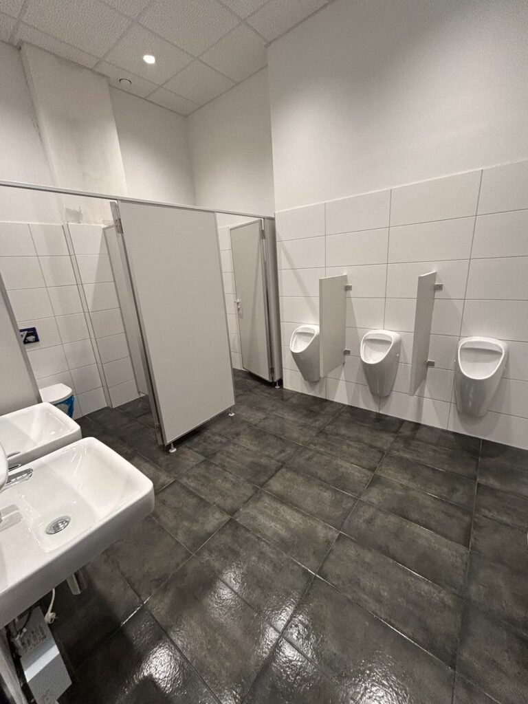 Gereinigtes Herren-WC mit drei Urinalen und Trennwänden