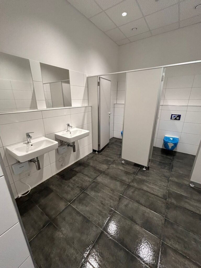Gereinigter Waschraum mit zwei Waschbecken und Spiegel