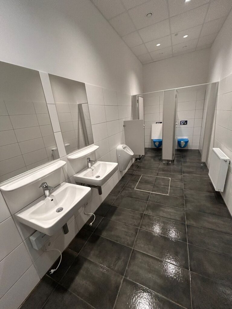 Gereinigter Sanitärbereich mit Waschbecken und WC-Trennwänden