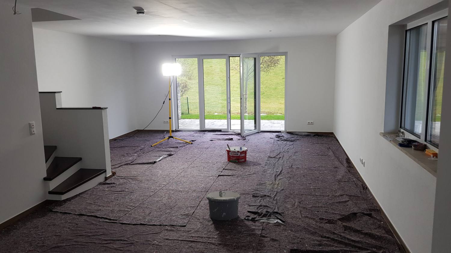 Großer Wohnraum mit komplett abgedecktem Boden und Baustrahler