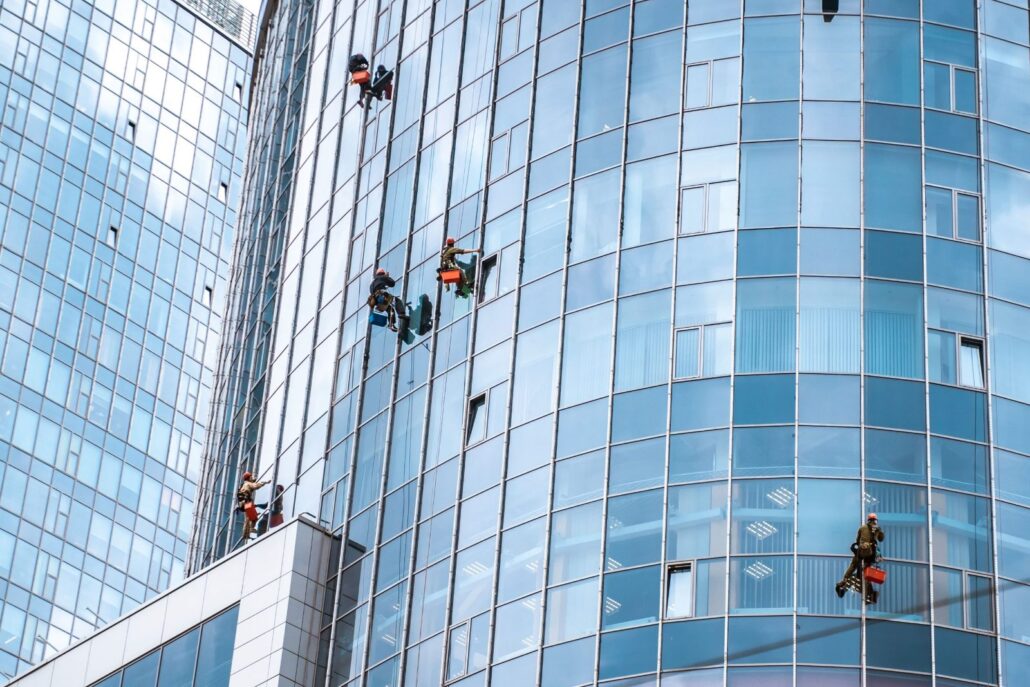 workers washing windows office building min scaled 1 Gebäudereinigung Ebersberg: Fensterputzer bei der Arbeit an einer Glasfassade