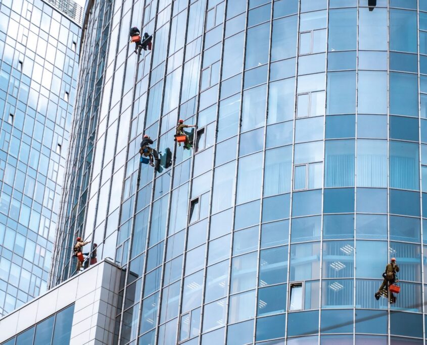 workers washing windows office building min scaled 1 Gebäudereinigung Ebersberg: Fensterputzer bei der Arbeit an einer Glasfassade