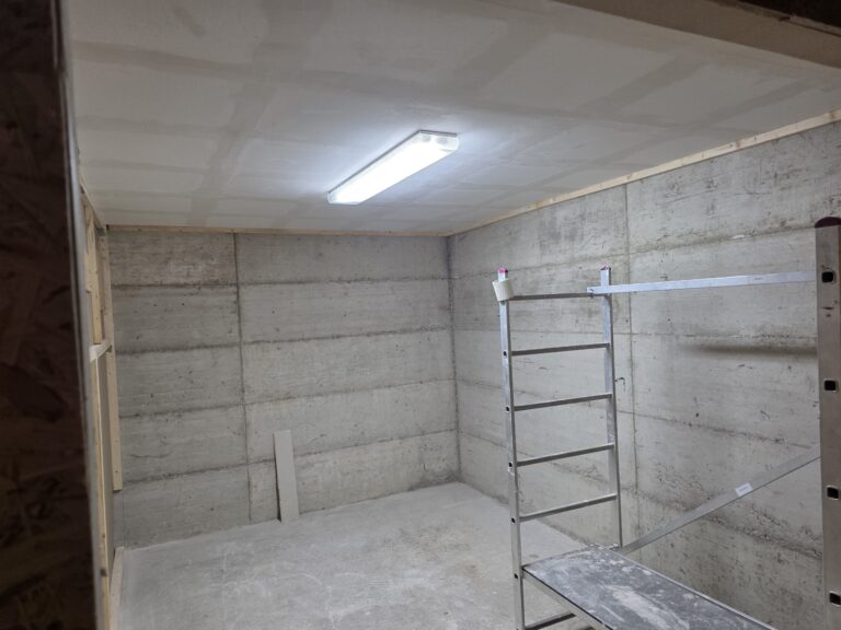Abgehängte Decke aus Gipskarton mit umlaufender Holzlatte an der Betonwand