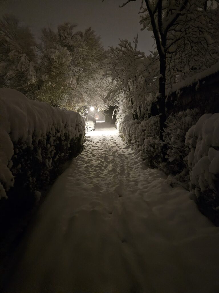Winterdienst: verschneiter Fußweg bei Nacht nach frischem Schneefall